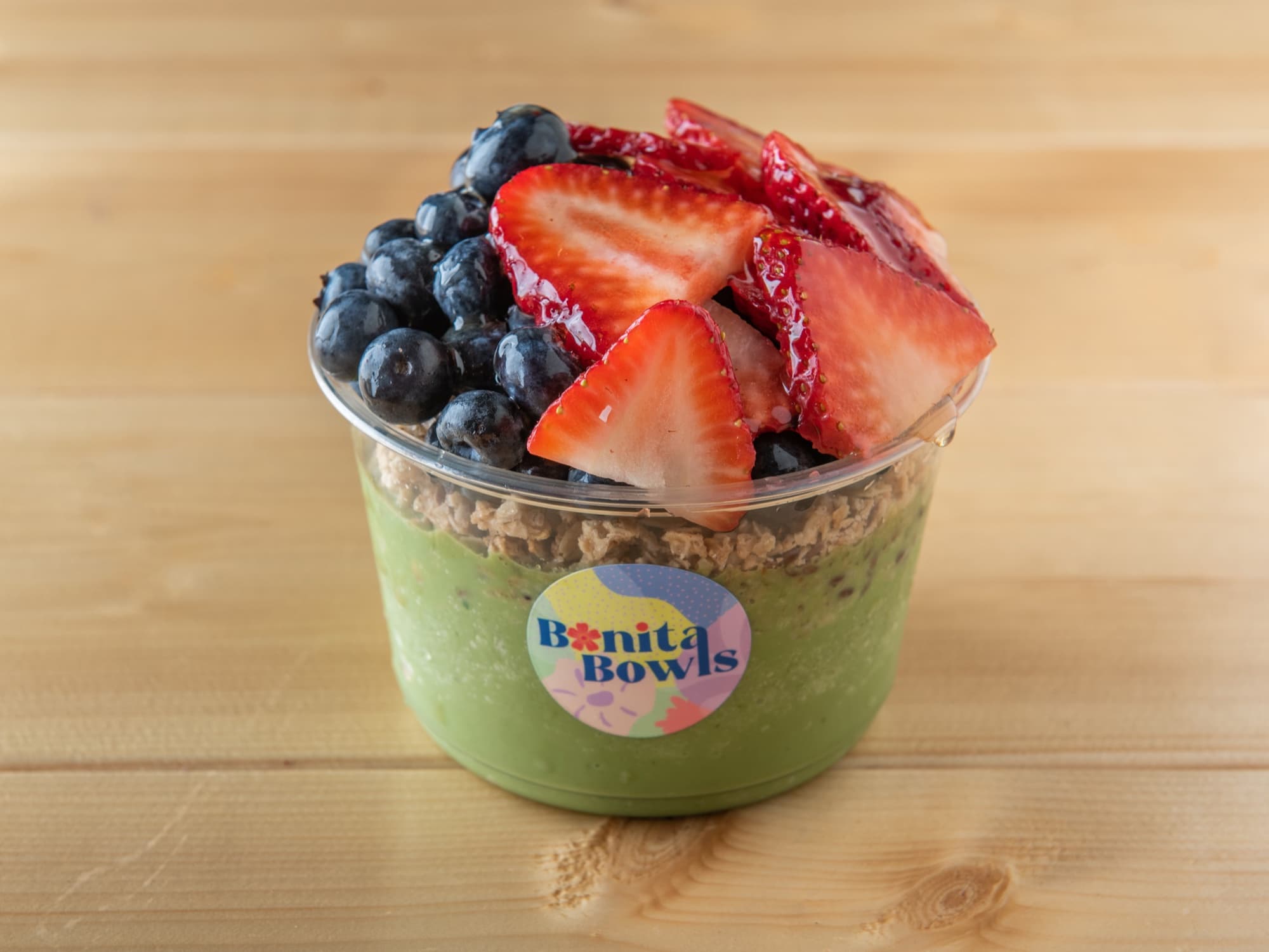 Pura Vida green-base smoothie bowl with strawberry, blueberry, and honey — the lowest-carb signature at Bonita Bowls